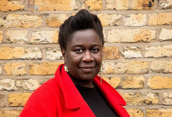 Artist Barby Asante wearing a red coat and looking at the camera