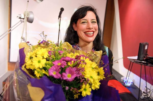 Artist Jessica Voorsanger smiling and holding a bunch of flowers