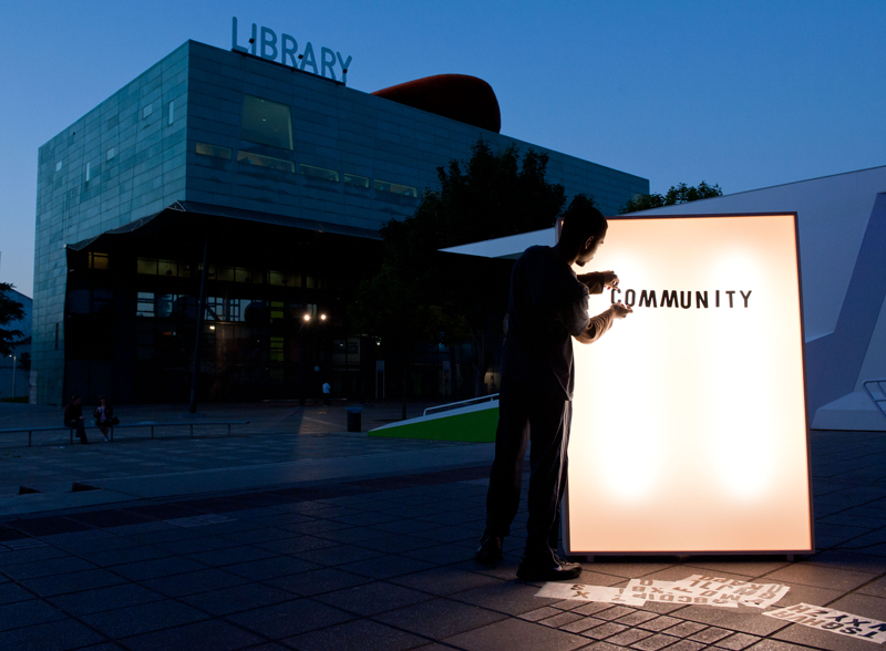 A person adding black letters to a lightbox outside Peckham library