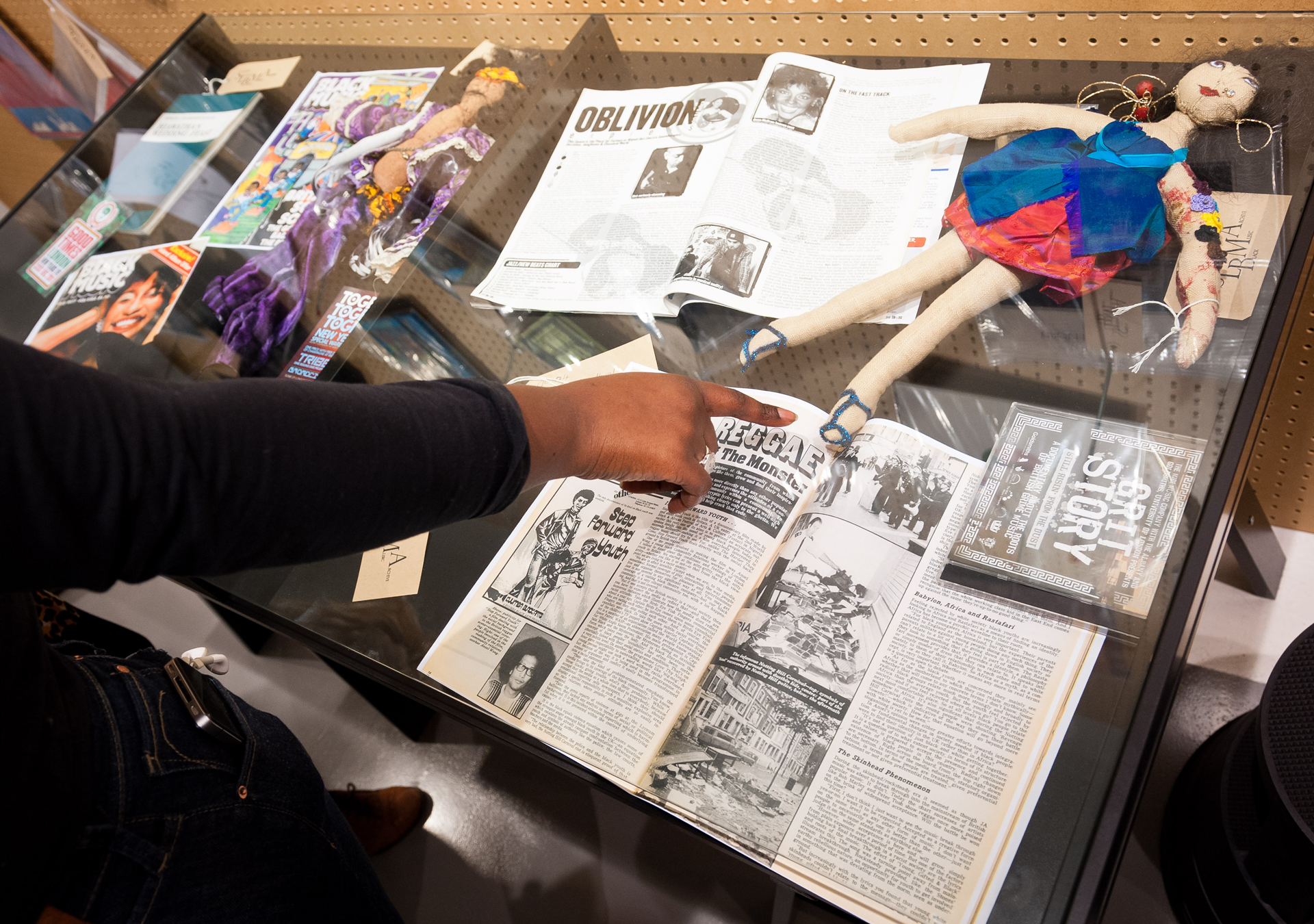 Arm pointing at a glass display from South London Black Music Archive exhibition