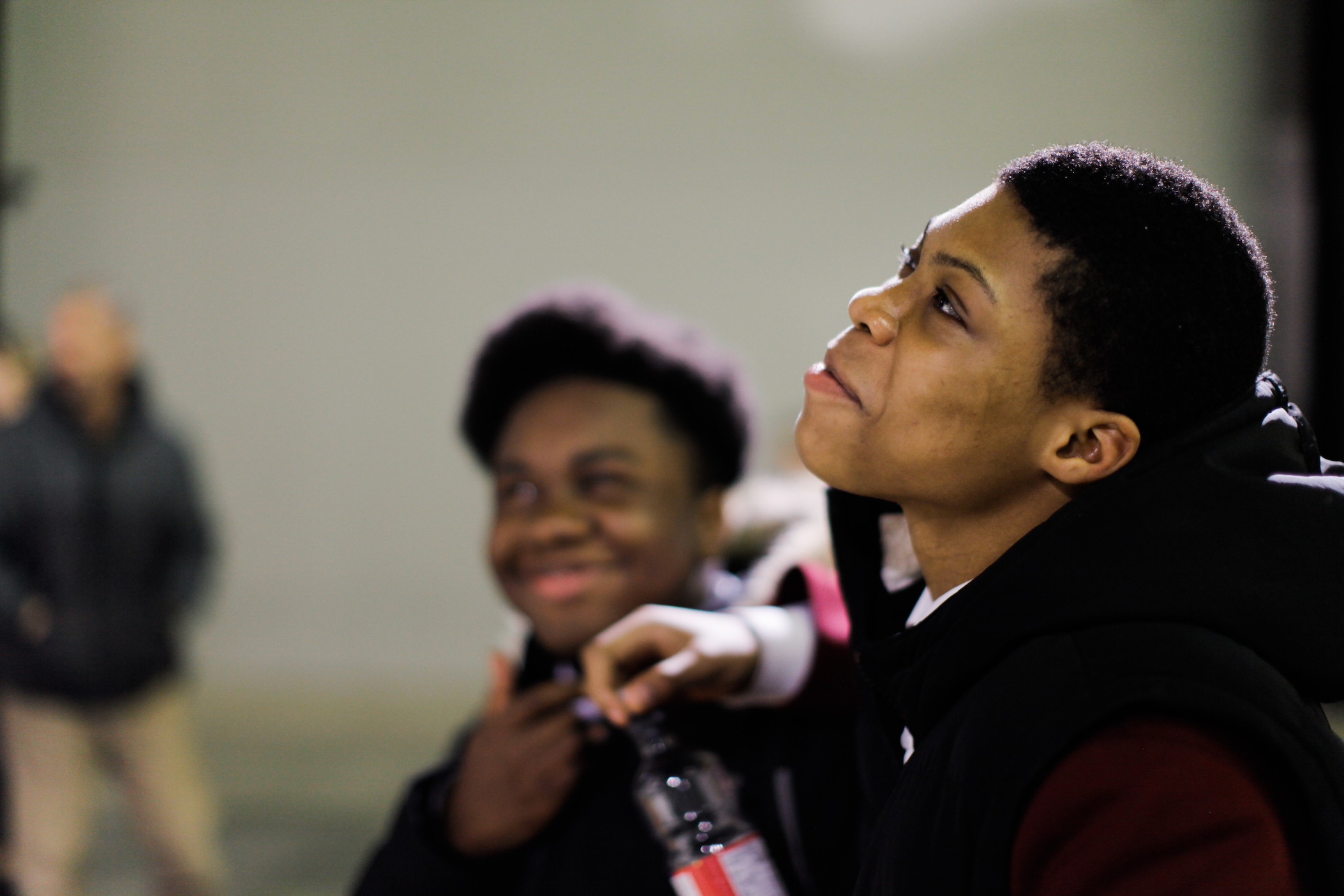 A brown-skinned teenager smiling while looking away from the camera